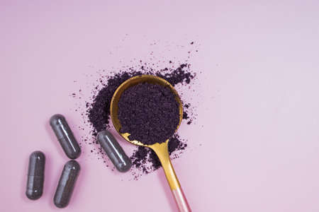 Bilberry or acai berry powder and pills on pink backgroundの写真素材