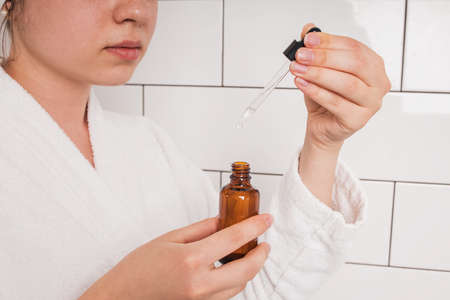 Hands of young woman after shower going to apply beauty serumの写真素材