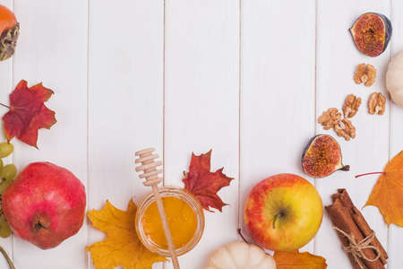 Pomegranates and dry leaves on yellow and green background. Creative Autumn layout. Border arrangement. Flat lay top view. Copy space.の写真素材