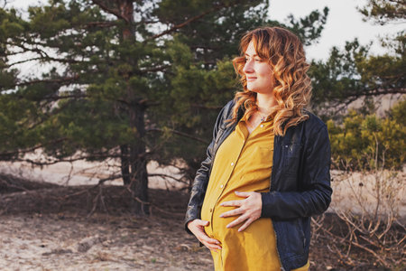 Young modern pregnant woman in yellow shirt and leather jacket outdoors