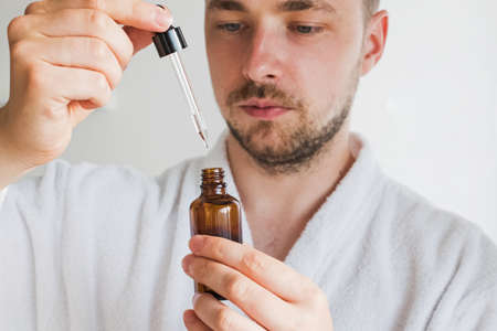 Young handsome man going to apply skin care product on his face.の写真素材