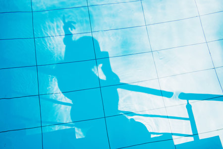 Woman taking photo of her shadow in swimming pool.