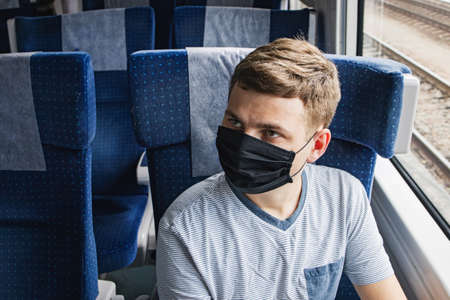 Young man wearing protective face mask sitting in the traingの写真素材