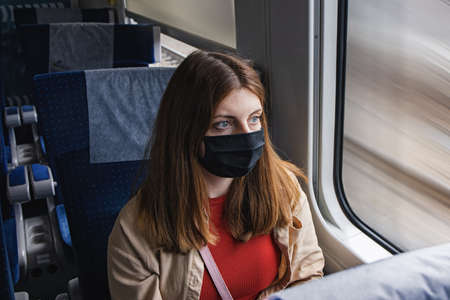 Young woman wearing protective face mask travelling by traing.の写真素材