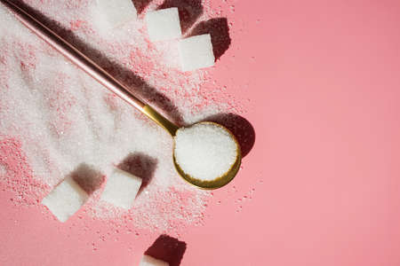 White sugar in the spoon and sugar cubes on pinkの写真素材