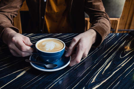 Close-up of man hand having a cup of cappuccinoの写真素材