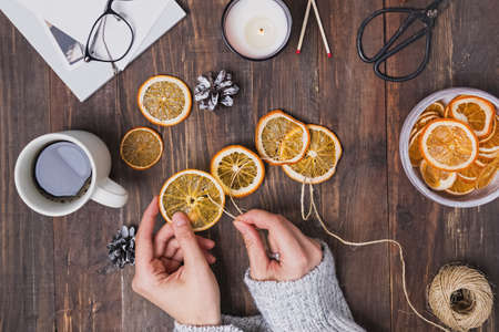 Womans hands making decorative wreath from dry orangesの写真素材