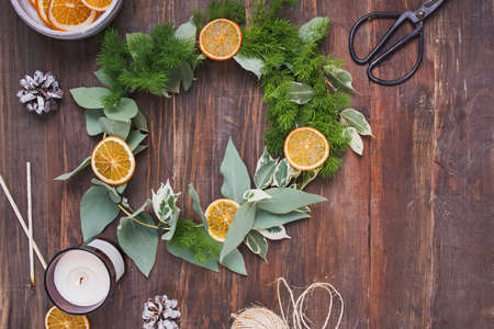 Hand made christmas wreath decorated with dry oranges on wooden tableの写真素材
