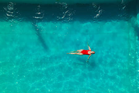 Woman in red bikini are swimming in the pool with turquoise waterの写真素材