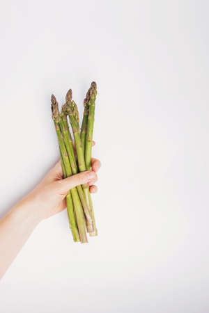 Female hand holds fresh green asparagus.の写真素材