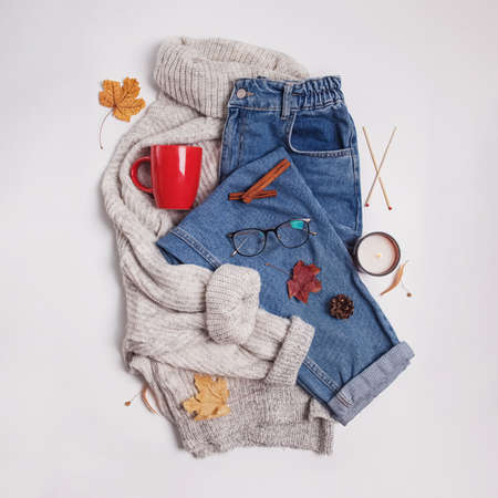 eans, knitted sweater, red cup and yellow leaves on white table, top viewの写真素材