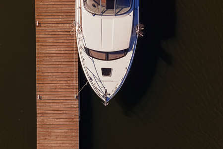 Aerial view photo of small motor boat or yacht standing near the wooden pierの写真素材