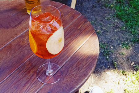 A glass of cold alcoholic drink with fruit slices and ice cubes.