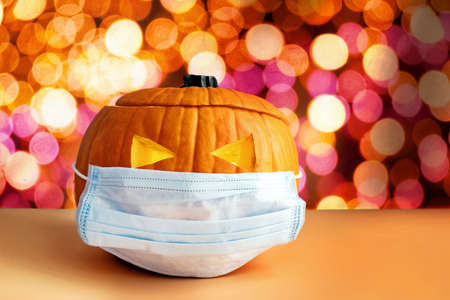 Pumpkin in a medical mask on the background of blurred lights.の写真素材