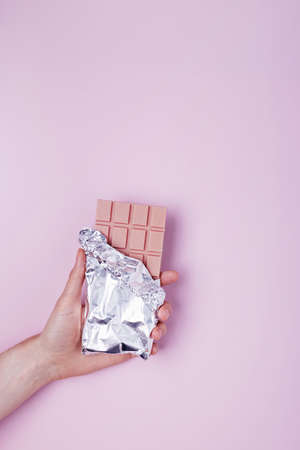 Feminine hand holds bar of raspberry flavored chocolteの写真素材