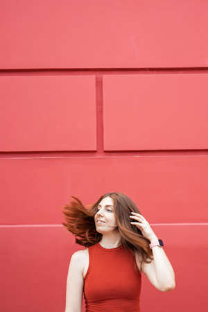Woman with long hair on red wall background.の写真素材