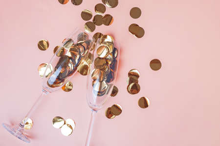 Golden confetti in champagne glasses on the peach color backgroundの写真素材