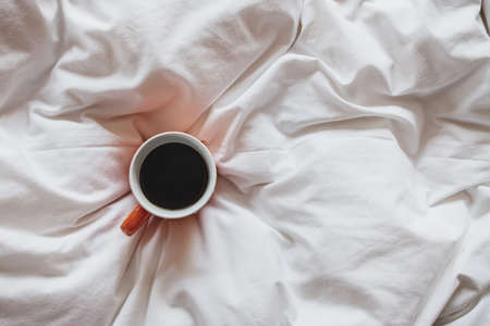 Cup of coffee on bed, top viewの写真素材