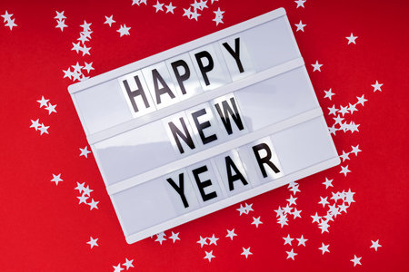 Happy New Year text on a lightbox with white star shaped confetti decor