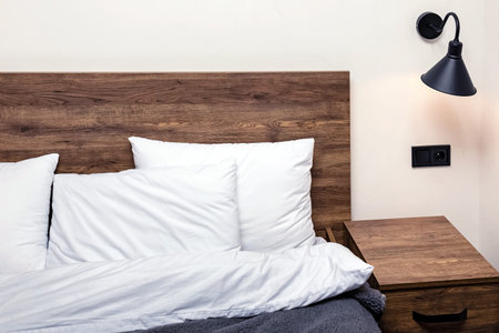 Modern minimalist bedroom interior. Bed with wooden headboard white pillows