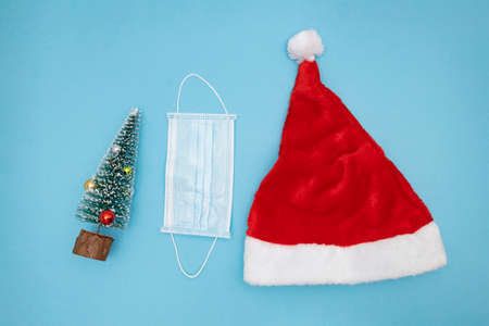 Santa Claus hat, small Christmas tree and protective face mask.の写真素材