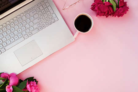 Laptop, peonies and coffee on pink tablの写真素材