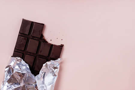 Bited bar of chocolate in foil with crumbsの写真素材