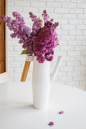 Bouquet of lilac in a white watering can on white tableの写真素材