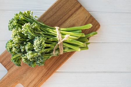 Raw broccolini green vegetable on wooden board. Healthy organic food, top view
