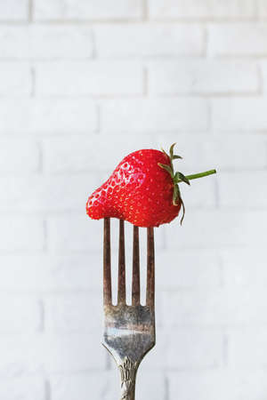Fresh red strawberry on a vintage design fork close-upの写真素材