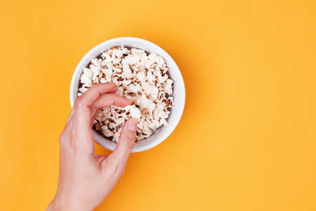 Womans hand taking popcorn from the bowlの写真素材