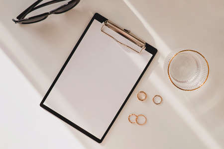 Blank paper, glass of water and rings on white tableの写真素材