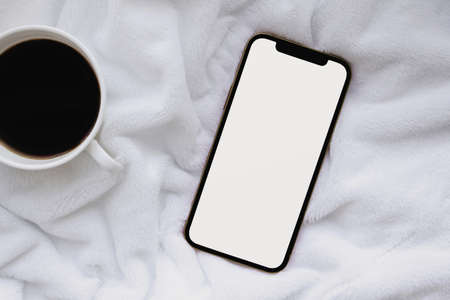 Phone and coffee on the bedの写真素材