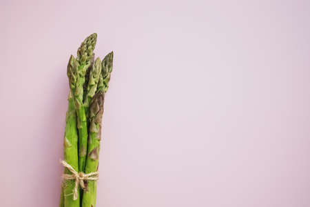 Bunch of raw ripe green asparagus on pink backgroundの写真素材