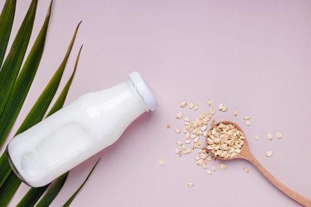 Bottle with daity free oat milk and dry oats in the spoon.