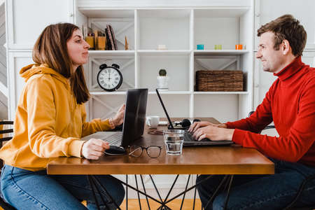 Man and woman working at home in the same room. Laughing to each otherの写真素材