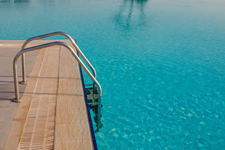 Ladder in swimming pool with turquoise waterの写真素材