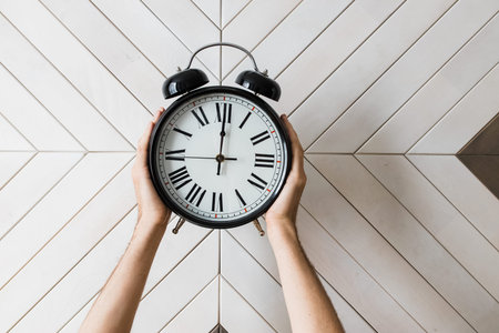 Male hand holding a big vintage alarm clock