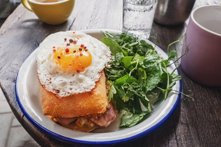 Sandwich with ham and fried egg on the top. Healthy breakfast on wooden table