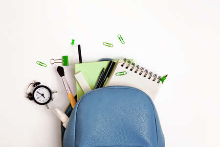 Students backpack with different stationery and study supplies on the white background, top view. Back to school concept.の写真素材