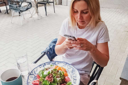 Woman sitting outside in cafe using her smartphone while eating lunch. Every day lifeの写真素材