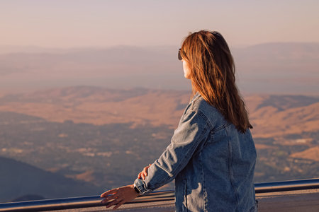 Woman in denim jacket enjoying warm weather with a viewの写真素材