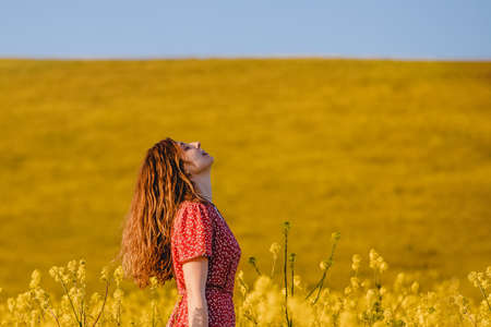 Portrait of young woman enjoying warm spring sunny weather outdoors in the blooming mustard fieldの写真素材