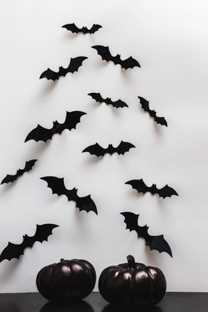 Black pumpkins and bat silhouettes on the white wall. Minimalist Halloween decor