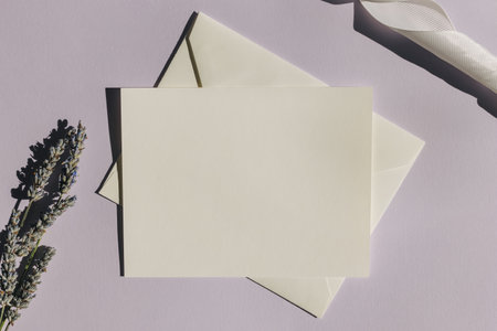 Blank paper card mock-up on pastel purple background with lavender flowers and shadows, top viewの写真素材