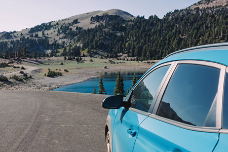 Blue car on the the roadside with a view on the mountain lake. Summer road trip
