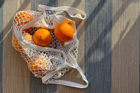 Mesh bag with oranges in natural sunlight, top viewの写真素材