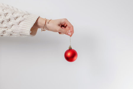 Woman's hand holding red decorative Christmas bauble over the white wallの写真素材