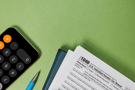 Tax season flat lay on green background. US individual tax form, pencil, smart phone glasses, top viewの写真素材