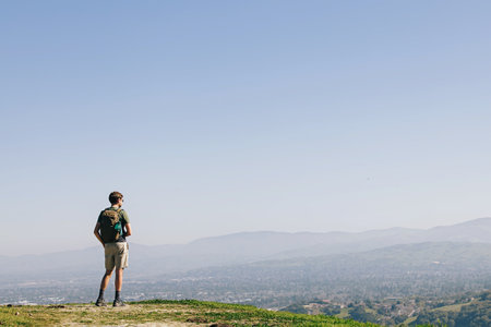 Man standing on the top of the hill with overview to the valley. Summer hiking.の写真素材